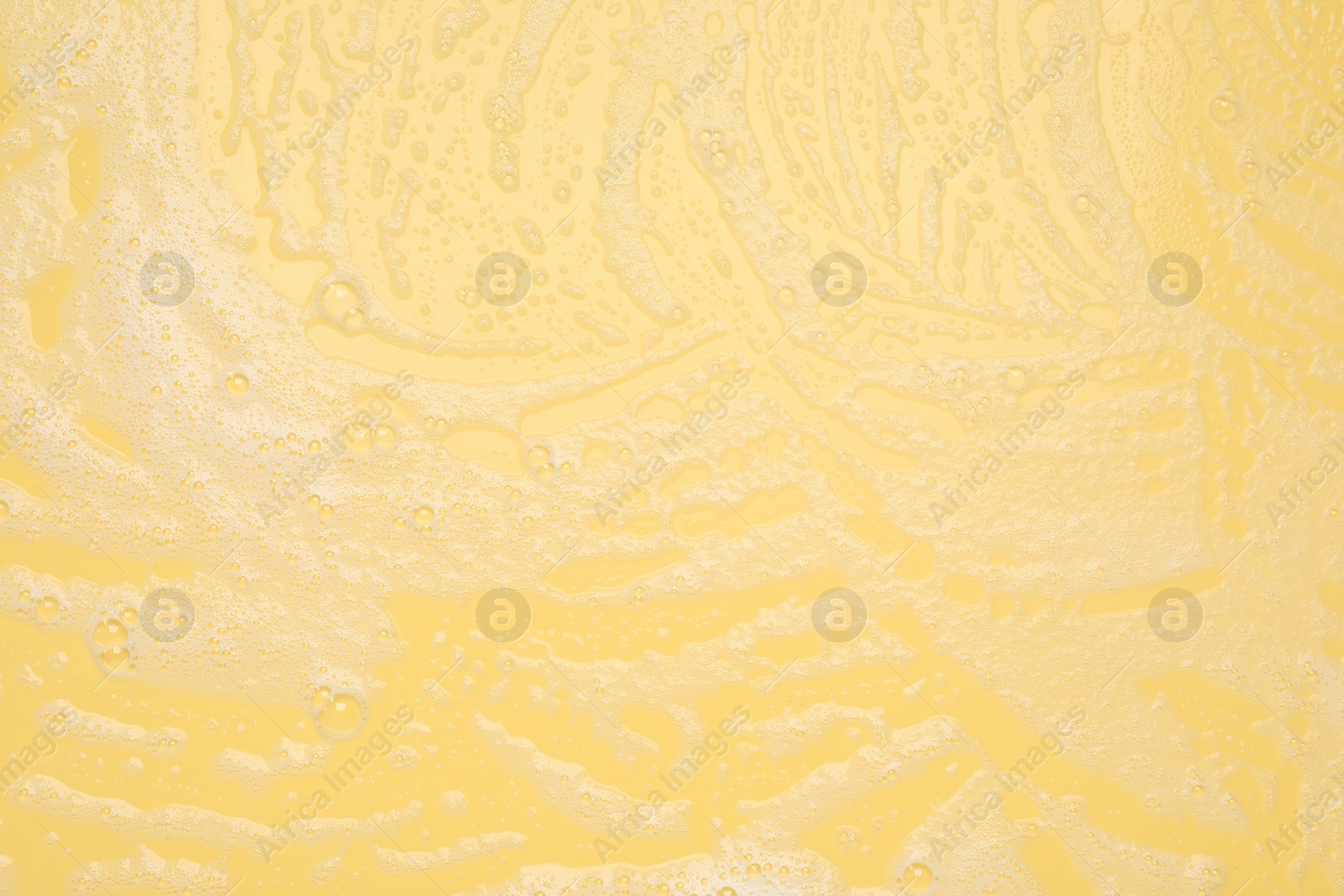 Photo of White washing foam on yellow background, top view