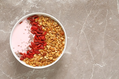 Photo of Smoothie bowl with goji berries on beige marble table, top view