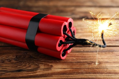 Dynamite bomb with lit fuse on wooden table, closeup