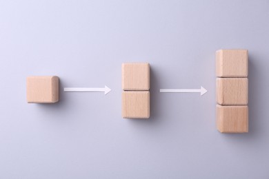 Business process organization and optimization. Scheme with wooden cubes and arrows on light grey background, top view