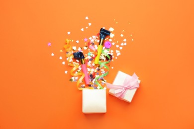 Photo of Beautiful flat lay composition with gift box and festive items on orange background. Surprise party concept