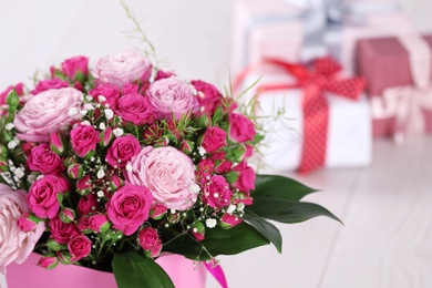 Beautiful bouquet of flowers and blurred gifts on background. Space for text