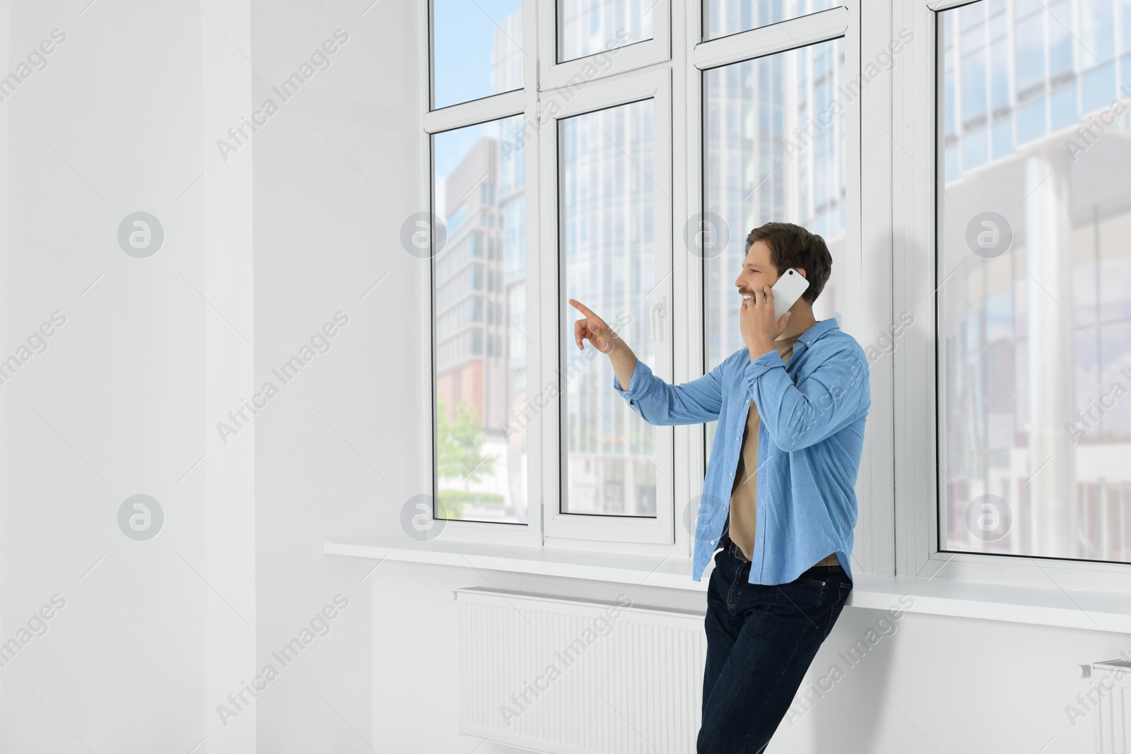 Photo of Man in casual clothes talking on phone indoors, space for text