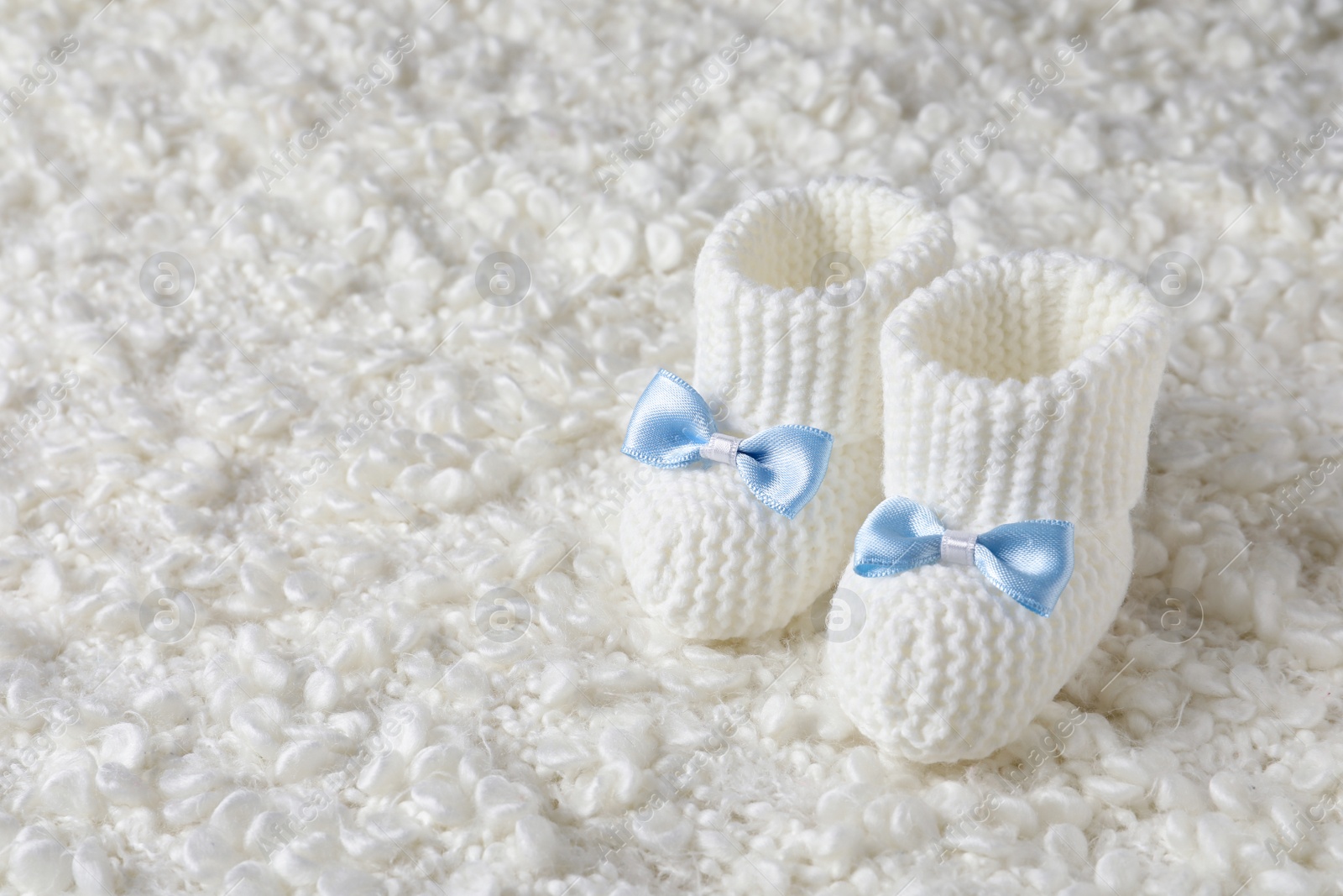 Photo of Handmade baby booties on soft plaid. Space for text
