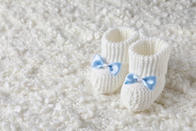 Handmade baby booties on soft plaid. Space for text