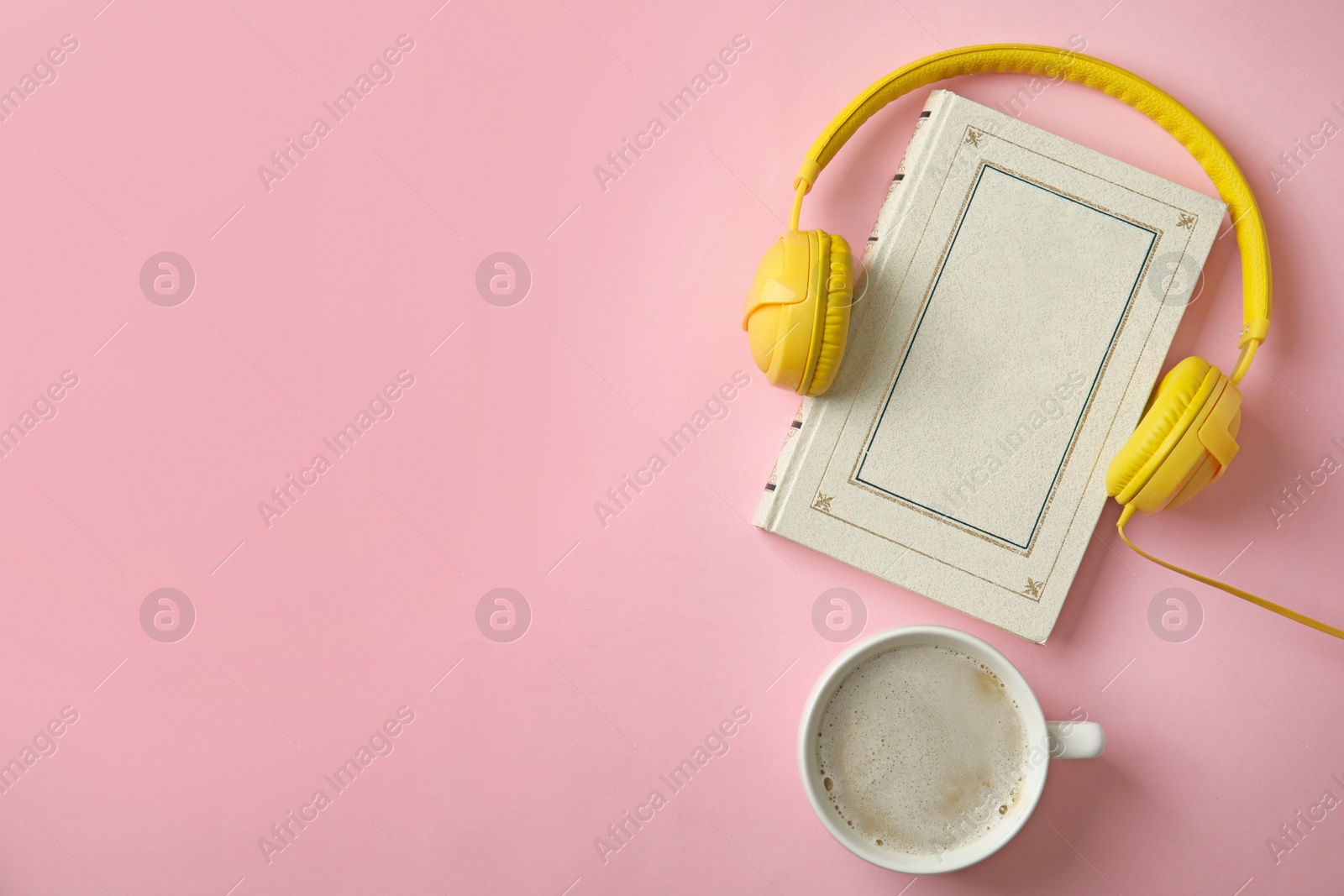 Photo of Modern headphones with hardcover book and coffee on pink background, top view. Space for text