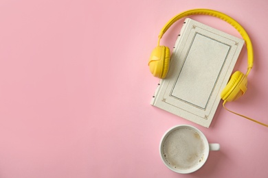 Photo of Modern headphones with hardcover book and coffee on pink background, top view. Space for text