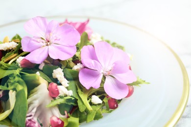 Photo of Fresh spring salad with flowers on white table, closeup
