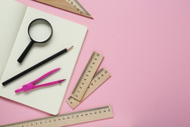 Different rulers, pencil, compass and magnifying glass on pink background, flat lay. Space for text