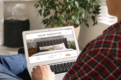 Image of Man using laptop to book hotel at home, closeup