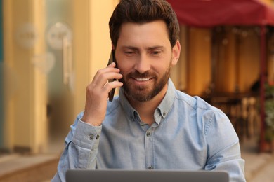Photo of Happy handsome man talking on phone outdoors