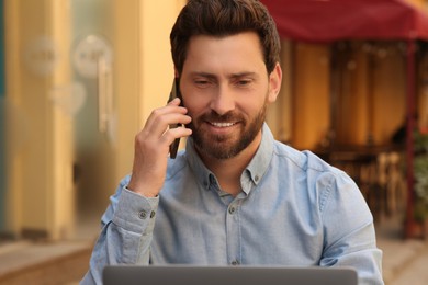 Happy handsome man talking on phone outdoors