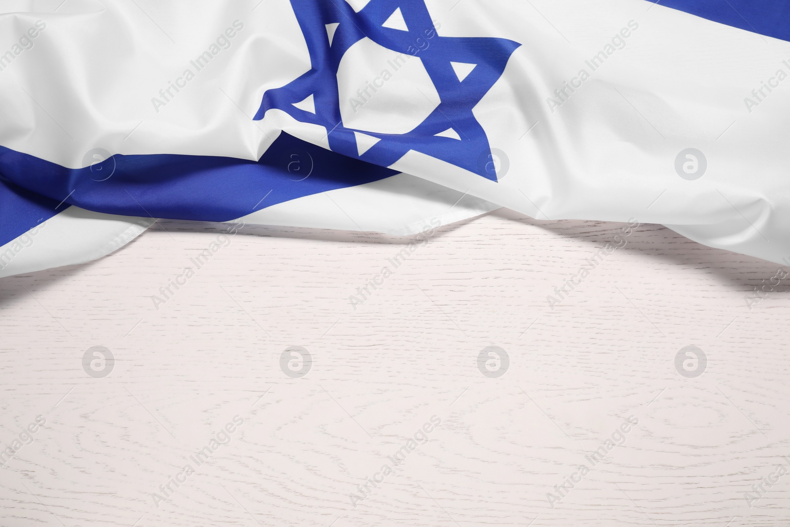 Photo of Flag of Israel on white wooden background, above view and space for text. National symbol