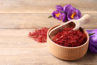 Dried saffron and crocus flowers on wooden table, space for text