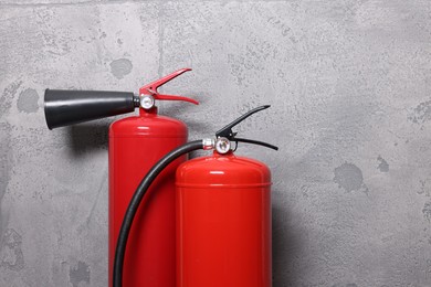 Photo of Red fire extinguishers near grey wall, space for text