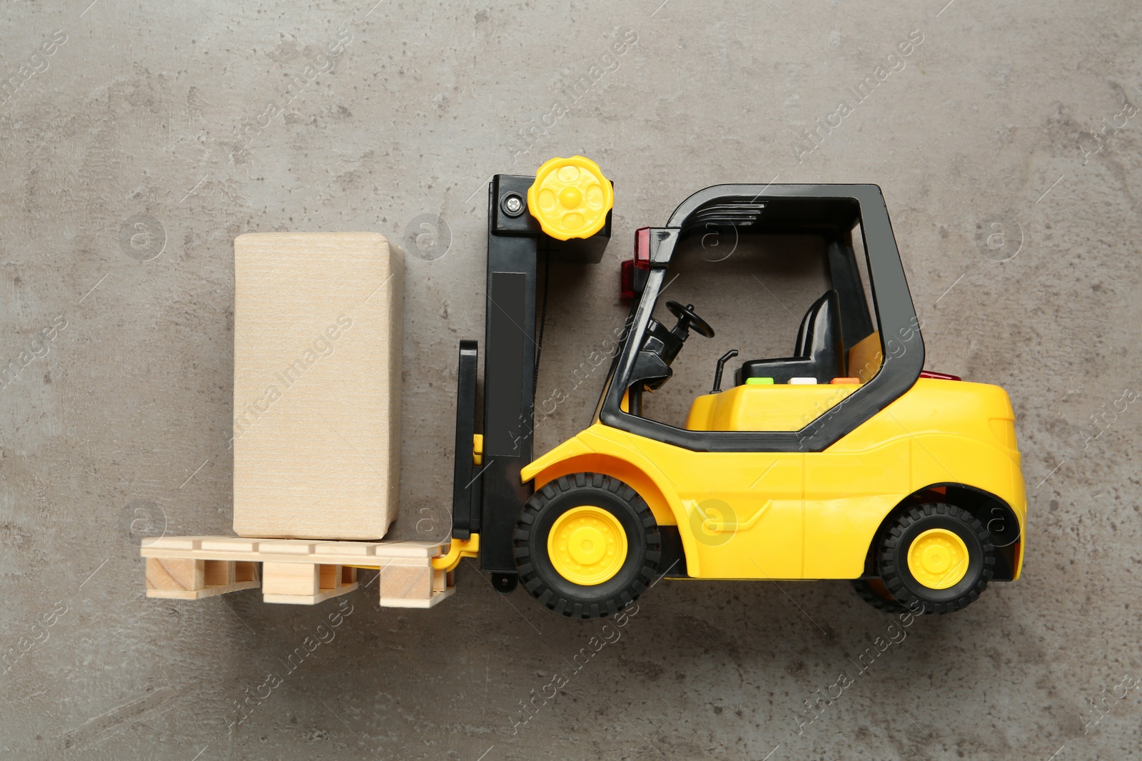 Photo of Toy forklift with wooden pallet and box on light grey table, top view