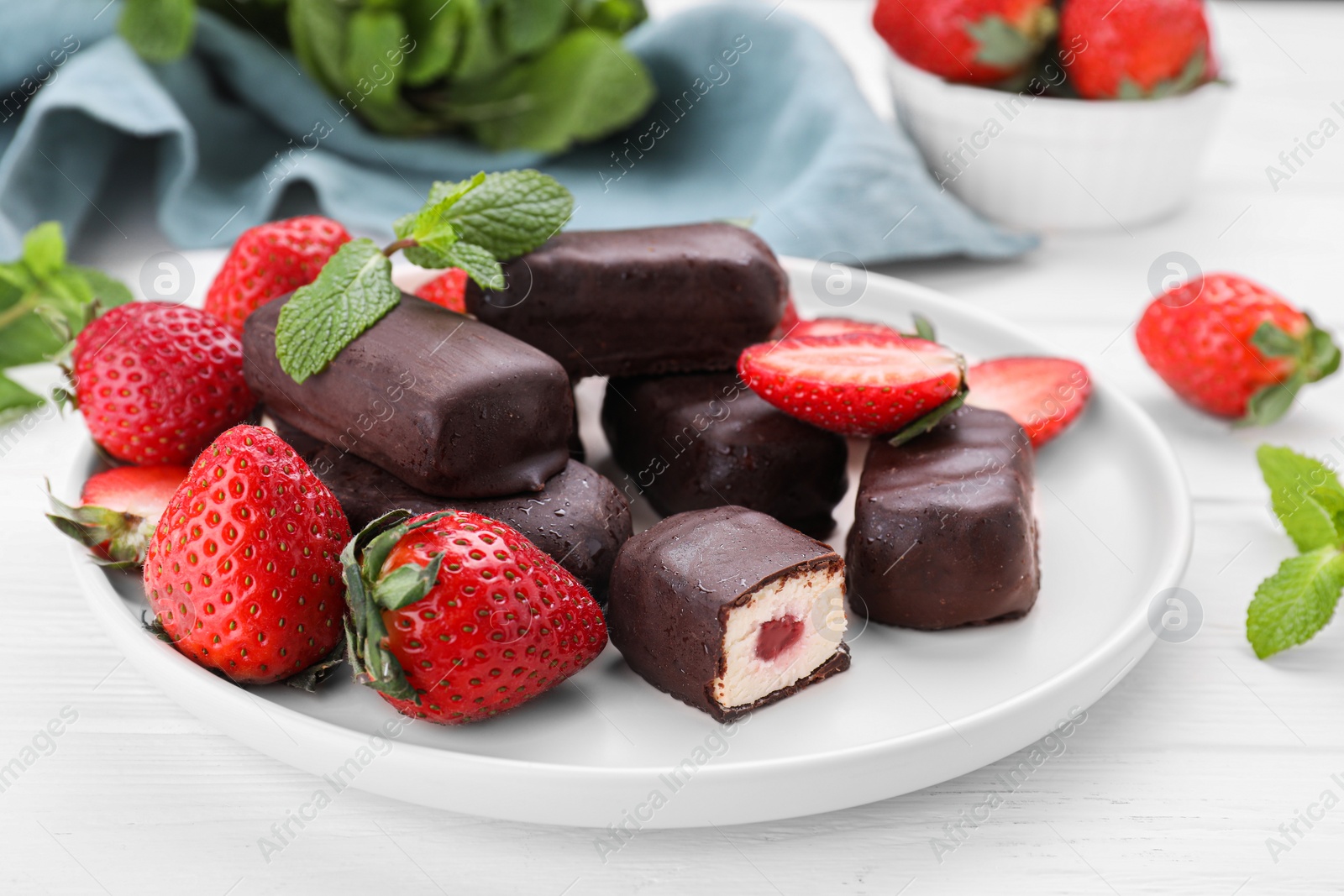 Photo of Delicious glazed curd snacks and fresh strawberries on white wooden table