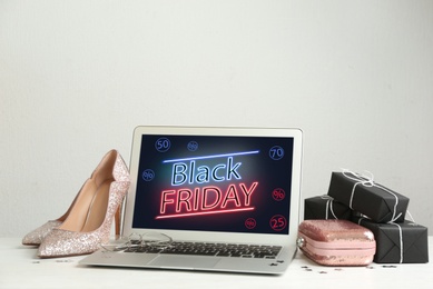 Photo of Composition with laptop and gifts on table against white background, space for text. Black Friday sale