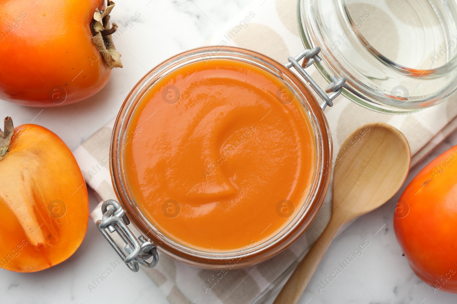 Photo of Delicious persimmon jam and fresh fruits on white table