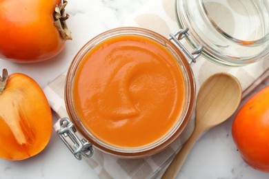 Photo of Delicious persimmon jam and fresh fruits on white table