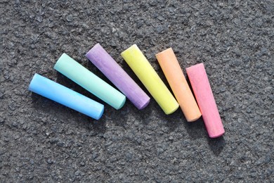 Photo of Colorful chalk sticks on asphalt, flat lay