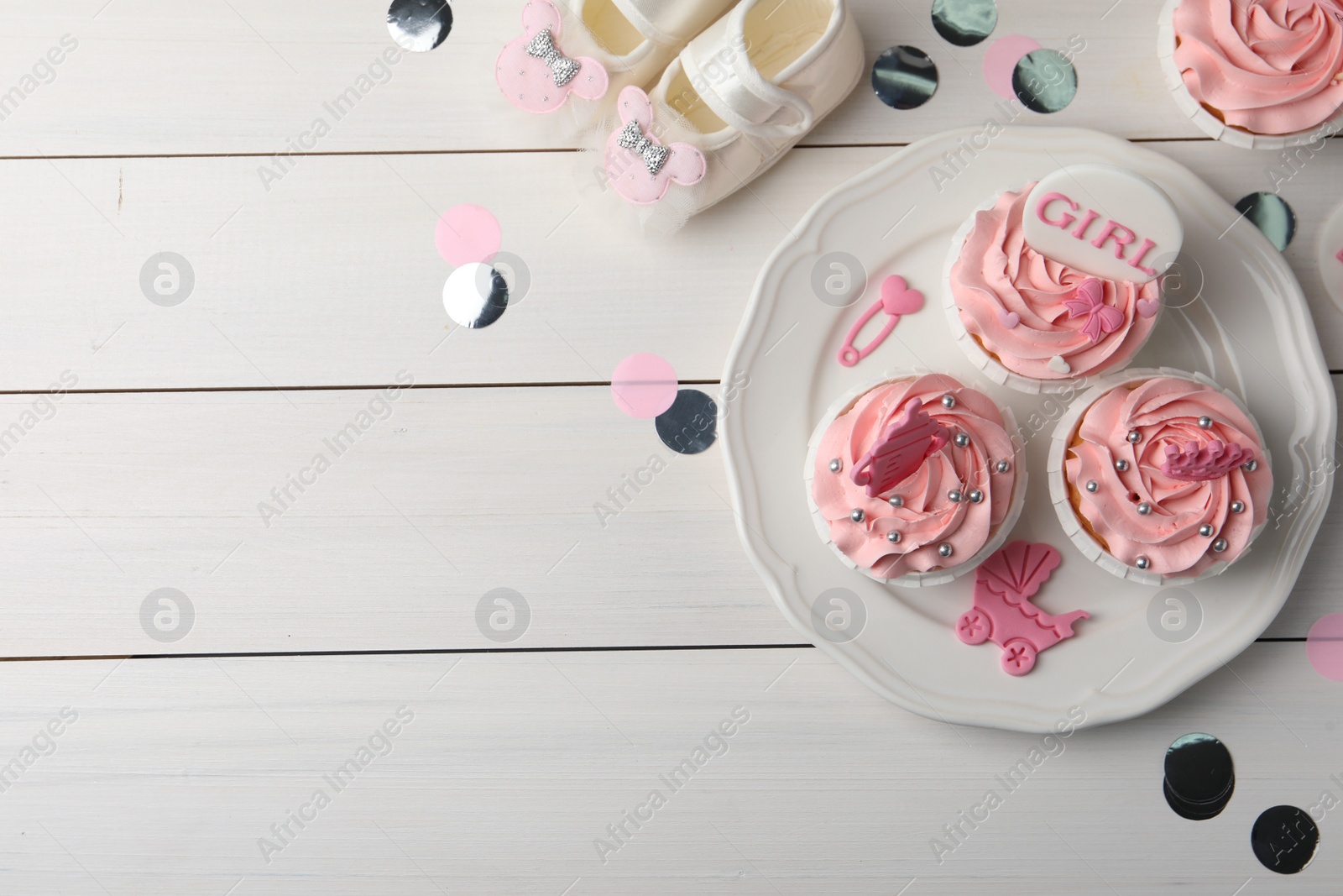 Photo of Delicious pink cupcakes on white wooden table, flat lay with space for text. Baby shower party