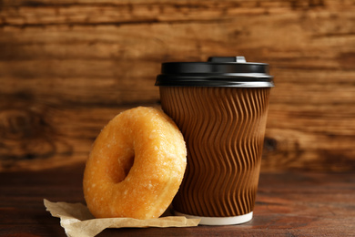 Photo of Delicious donut and cup of coffee on wooden table