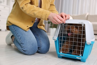 Photo of Woman closing carrier with her pet before travelling indoors, closeup