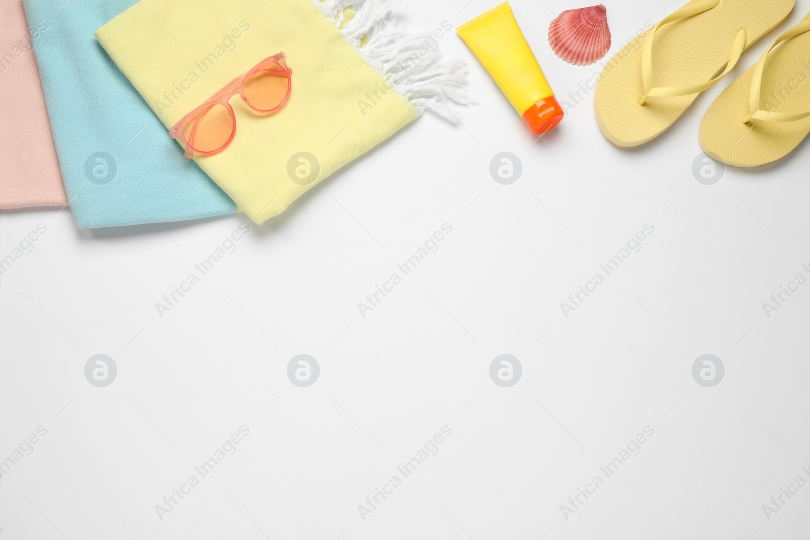 Photo of Beach towel, flip flops, sunglasses and sun protection product on white background, flat lay. Space for text