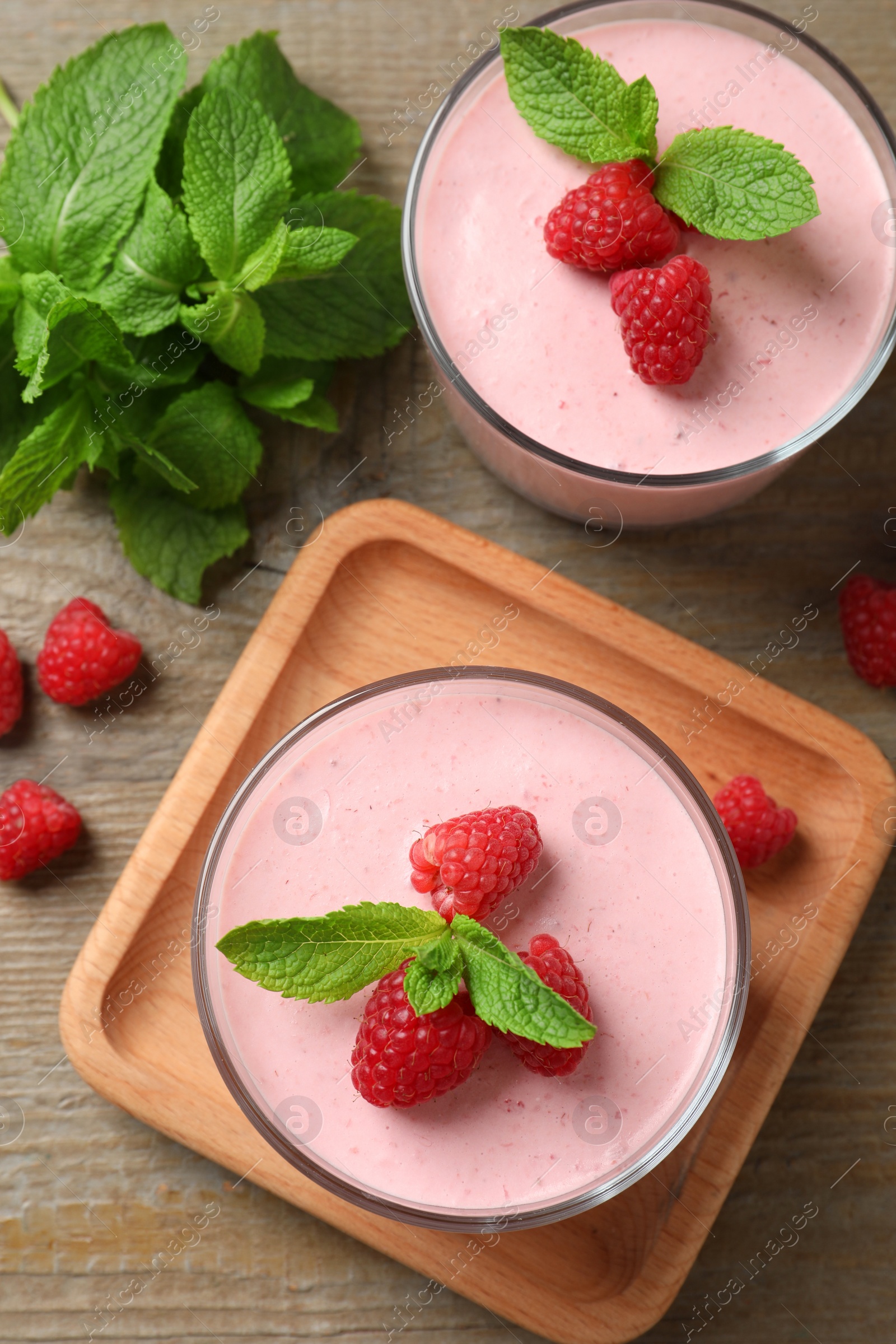 Photo of Delicious raspberry mousse with mint on wooden table, flat lay