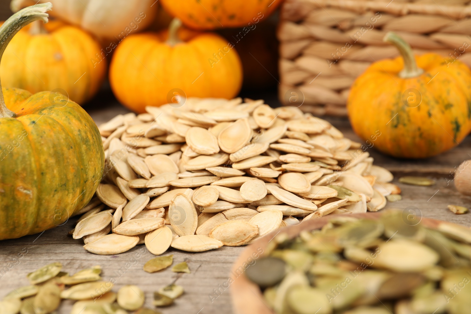 Photo of Many fresh pumpkins and seeds on wooden table, closeup