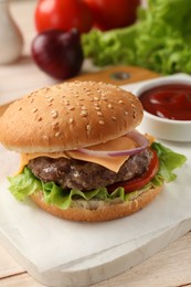 Photo of Tasty hamburger with patty, cheese and vegetables on light table