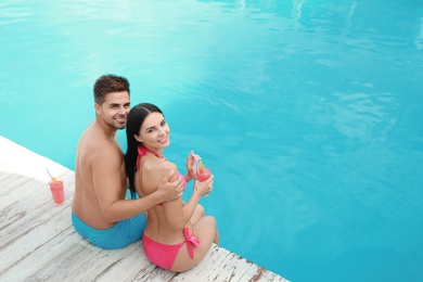 Woman in bikini with boyfriend near outdoor pool. Happy young couple