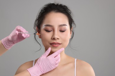 Photo of Woman getting facial injection on grey background