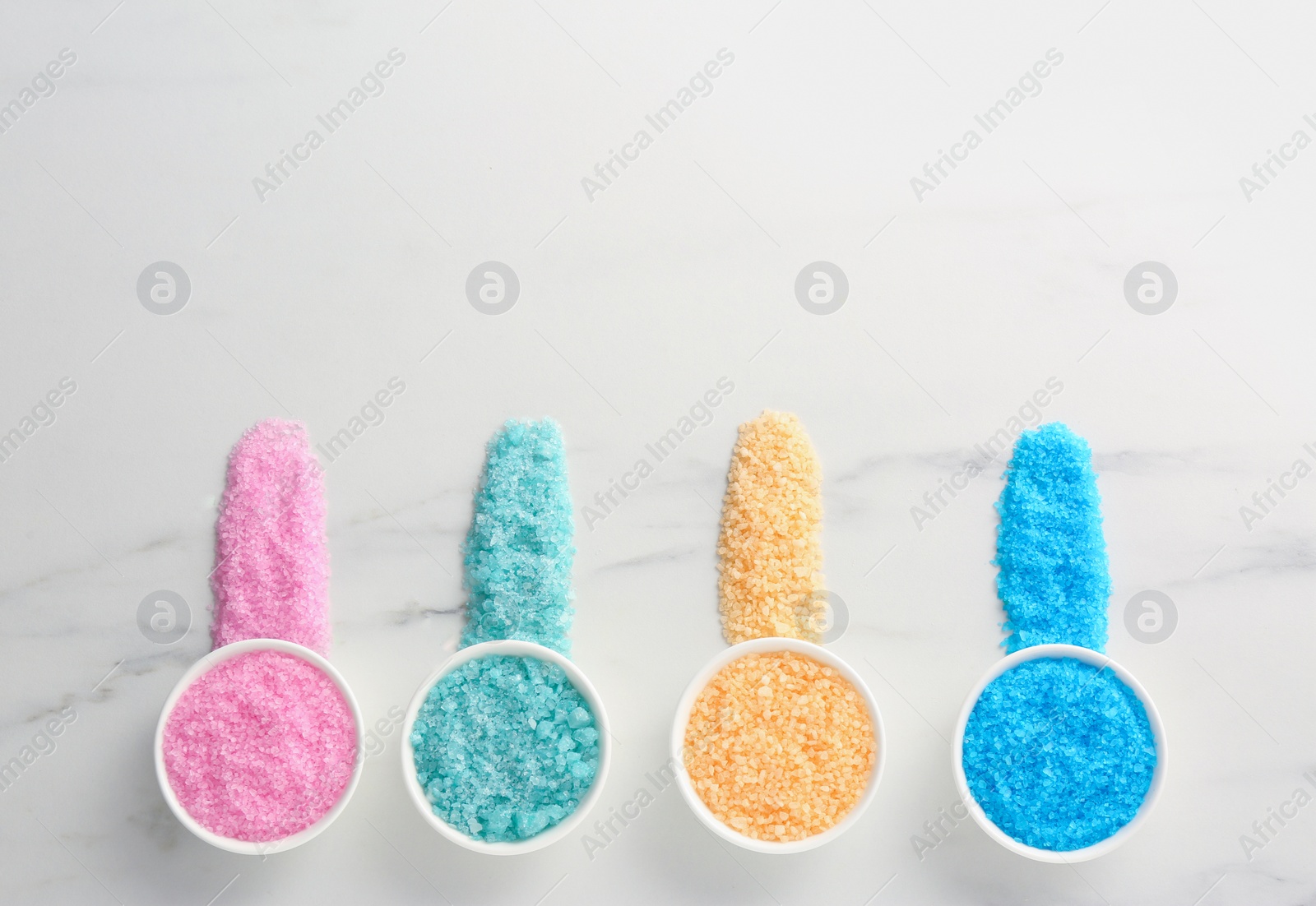 Photo of Many bowls with colorful sea salt on white marble table, flat lay. Space for text