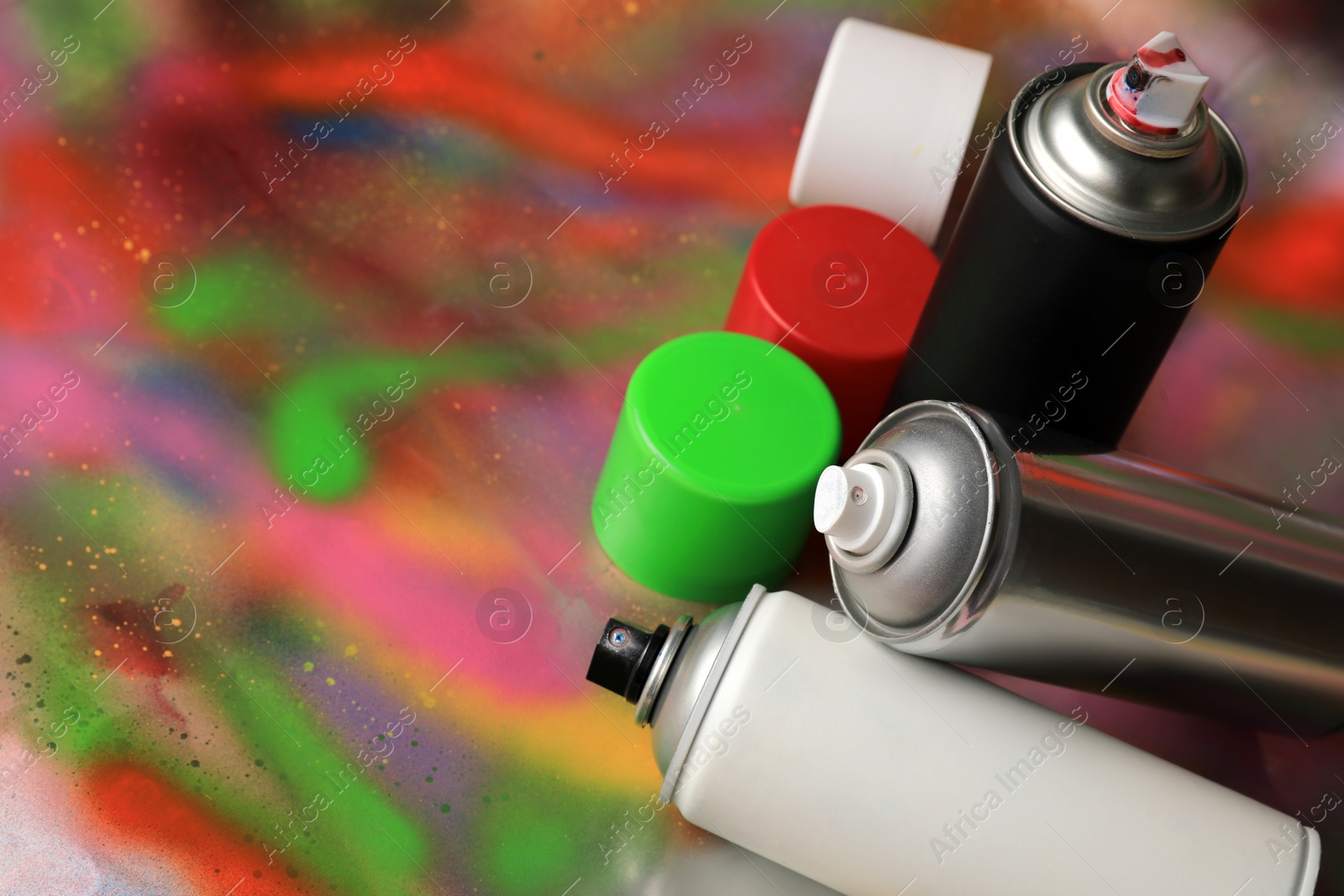 Photo of Cans of different graffiti spray paints on color background, space for text
