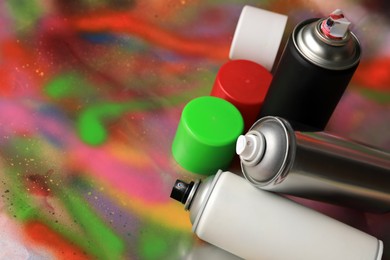 Cans of different graffiti spray paints on color background, space for text