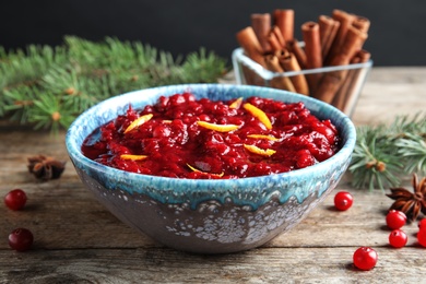 Photo of Bowl of tasty cranberry sauce with citrus zest on table