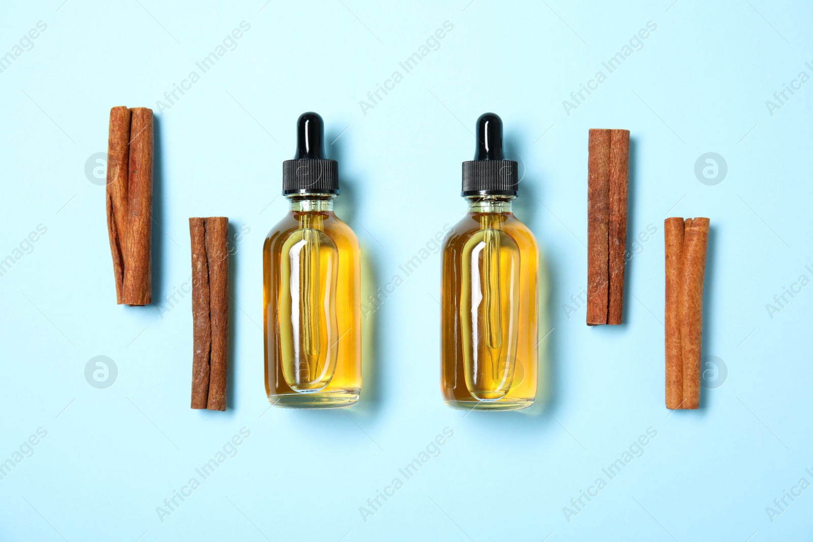 Photo of Flat lay composition with cinnamon essential oil on blue background