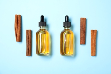 Photo of Flat lay composition with cinnamon essential oil on blue background