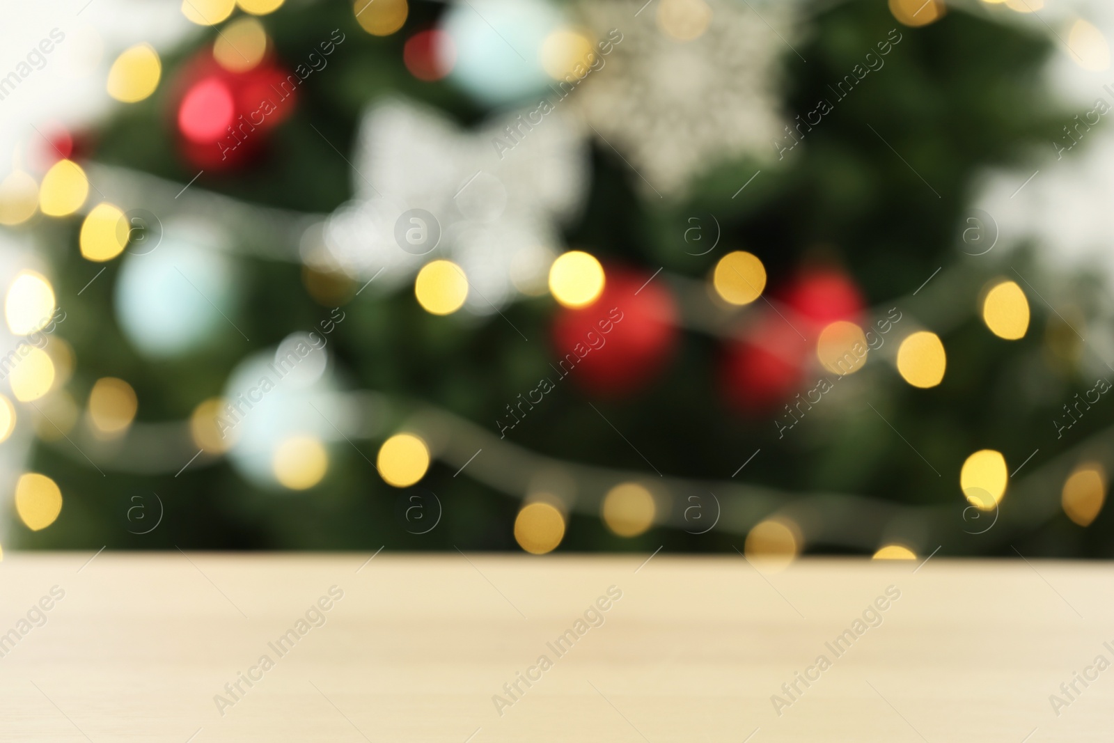 Photo of Empty wooden table against fir tree with Christmas lights, blurred view. Space for design