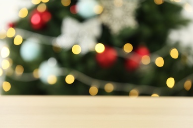 Photo of Empty wooden table against fir tree with Christmas lights, blurred view. Space for design