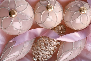 Photo of Set of beautiful Christmas baubles and ribbon on pink paper, flat lay
