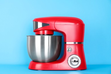 Photo of Modern red stand mixer on turquoise background