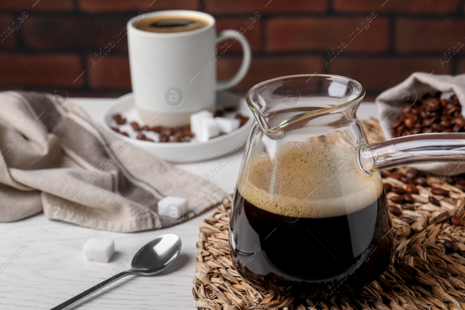Photo of Turkish coffee. Glass cezve with hot aromatic coffee on white wooden table, space for text