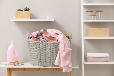 Photo of Wicker basket with dirty laundry on table indoors