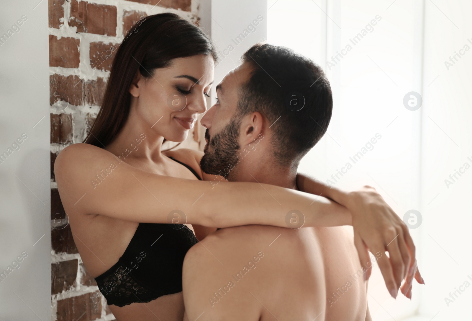 Photo of Passionate young couple having sex near brick wall indoors