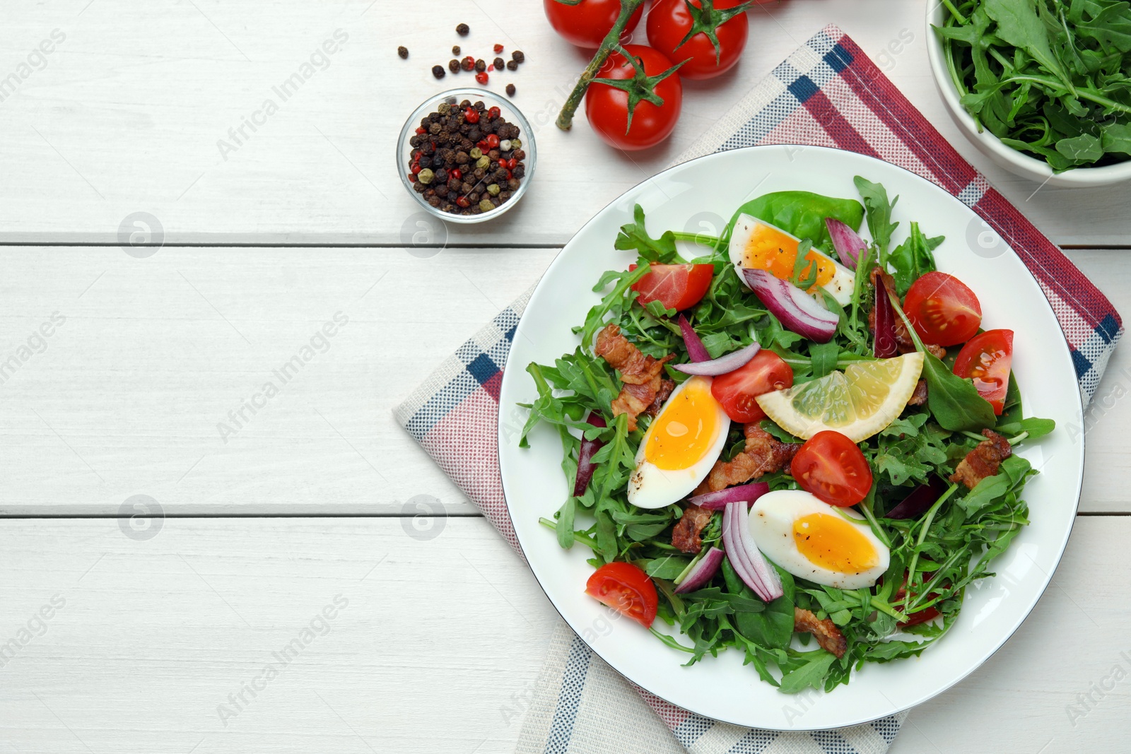 Photo of Delicious salad with boiled eggs, vegetables and bacon served on white wooden table, flat lay. Space for text