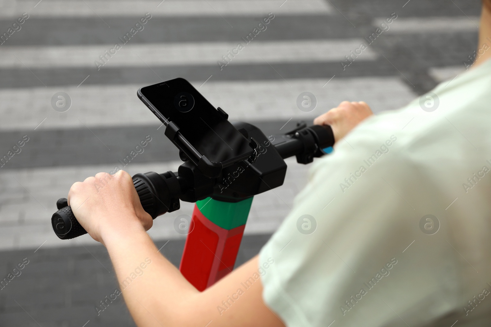 Photo of Woman riding modern electric kick scooter with smartphone outdoors