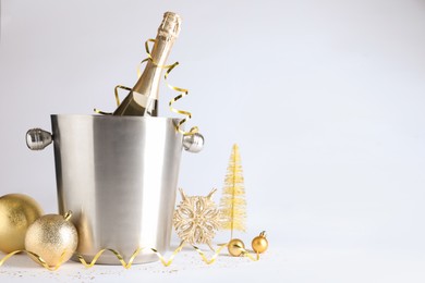 Photo of Happy New Year! Bottle of sparkling wine in bucket and festive decor on white background, space for text